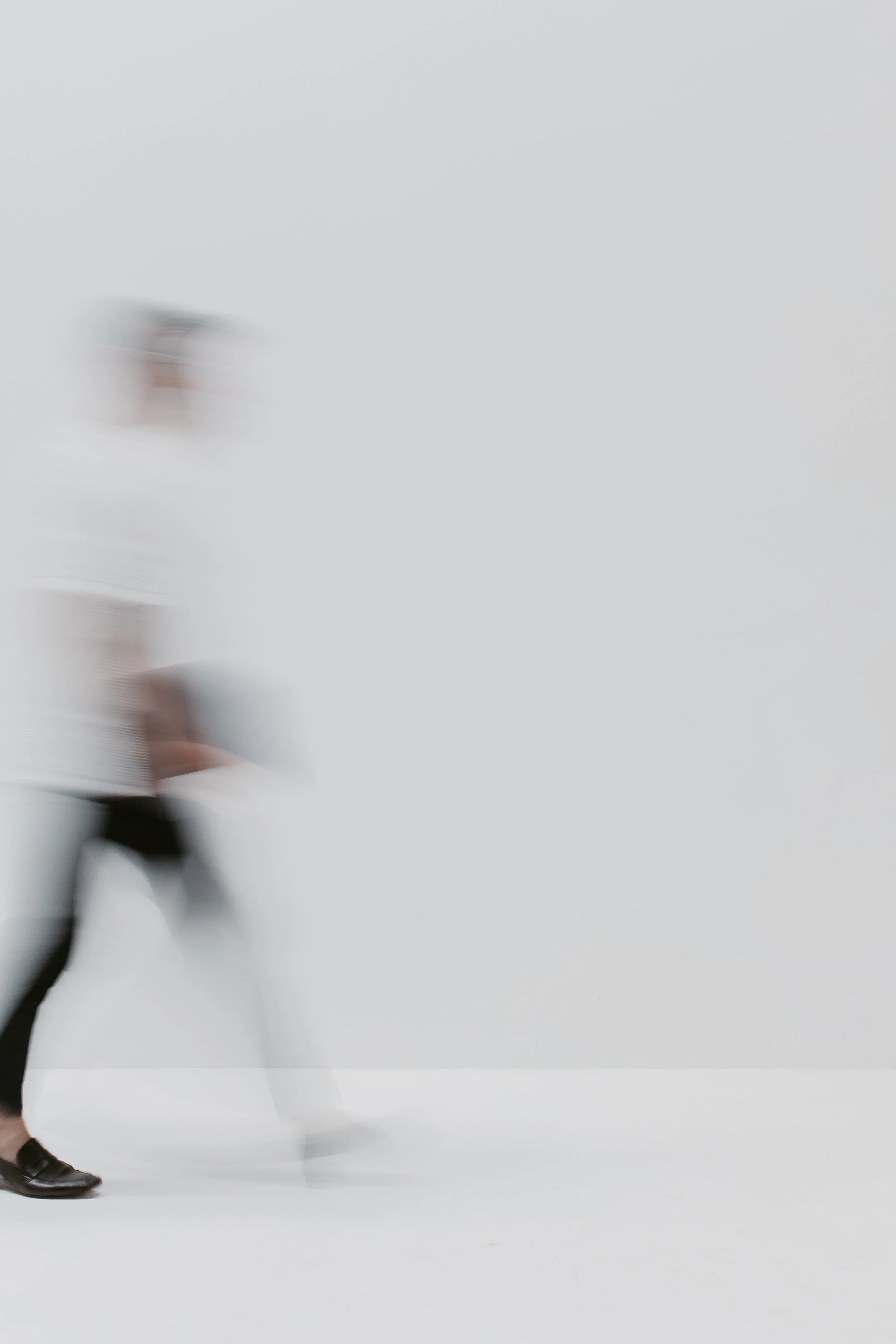 Motion-blurred figure walking in a pale studio