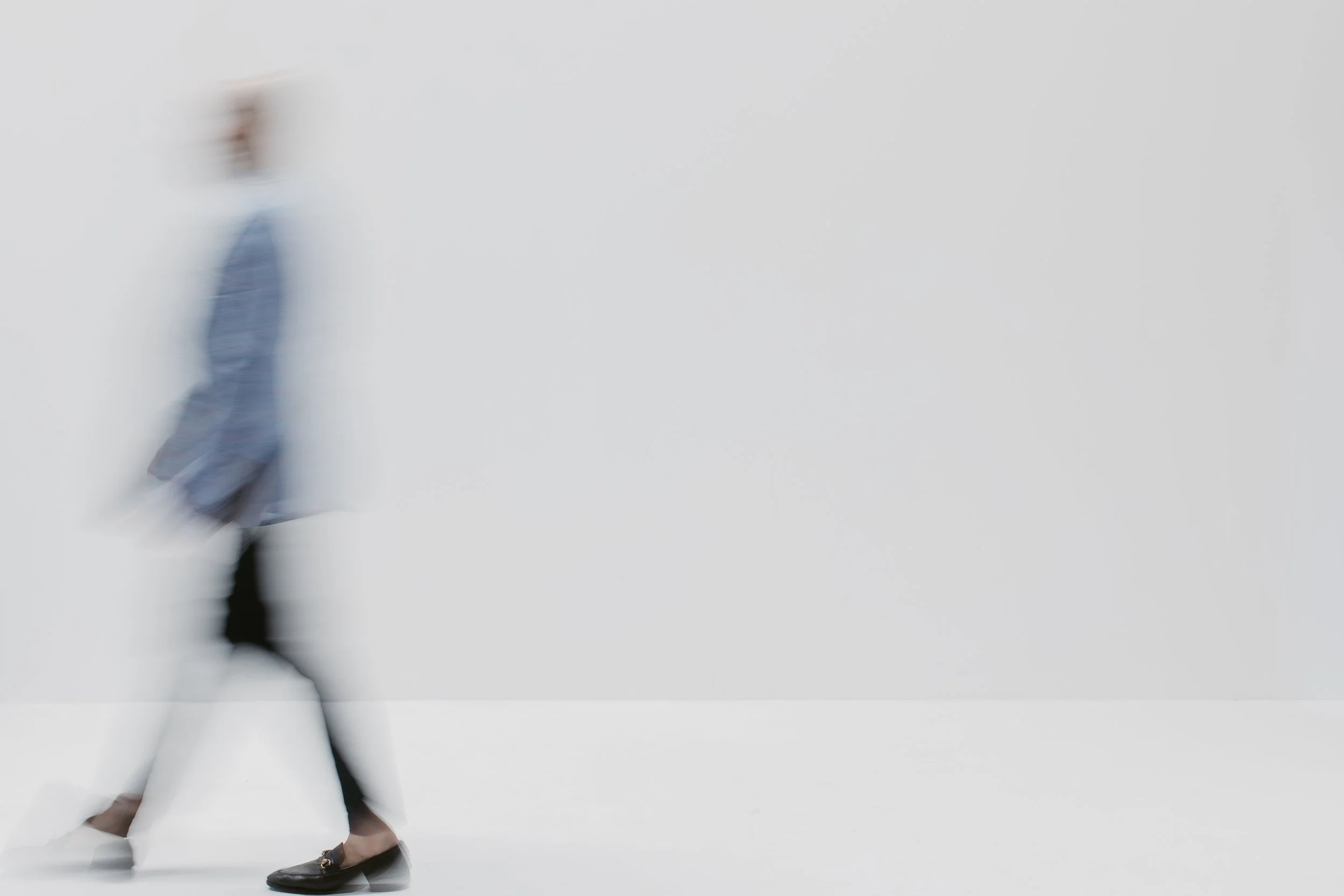Motion-blurred figures crossing a pale studio floor